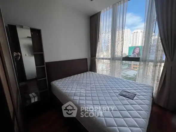 Spacious bedroom with large window offering city views, featuring a comfortable bed and modern decor.