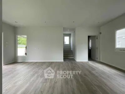 Spacious modern living room with elegant flooring and ample natural light.