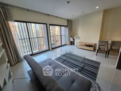Spacious modern living room with city view, featuring sleek furniture and large windows.