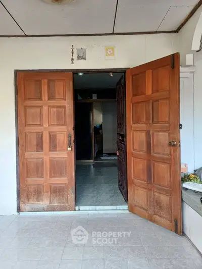 Inviting wooden double doors open to a cozy interior space with tiled flooring.