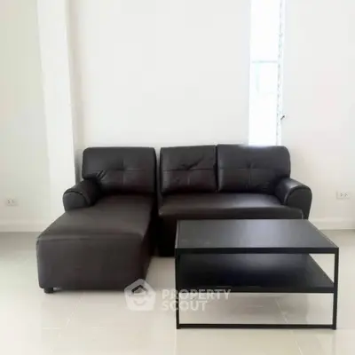 Modern living room with sleek black leather sofa and minimalist coffee table.