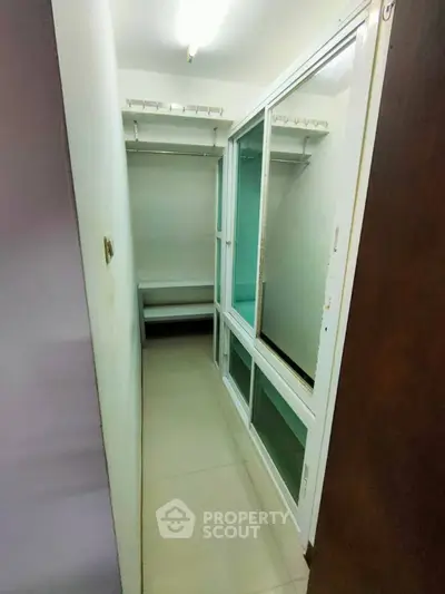 Compact walk-in closet with sliding glass doors and ample shelving
