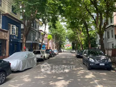 Charming tree-lined residential street with parked cars and classic architecture.