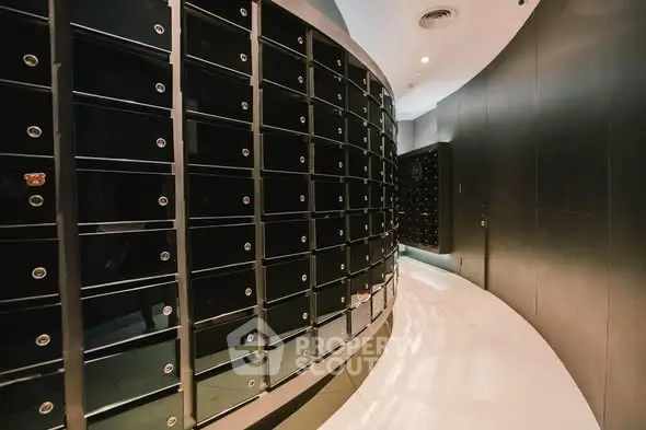 Modern apartment building mailroom with sleek black mailboxes and curved walls.