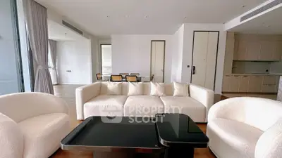 Spacious modern living room with elegant white furniture and open kitchen layout.