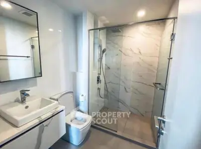 Modern bathroom with glass shower and sleek fixtures in contemporary home.