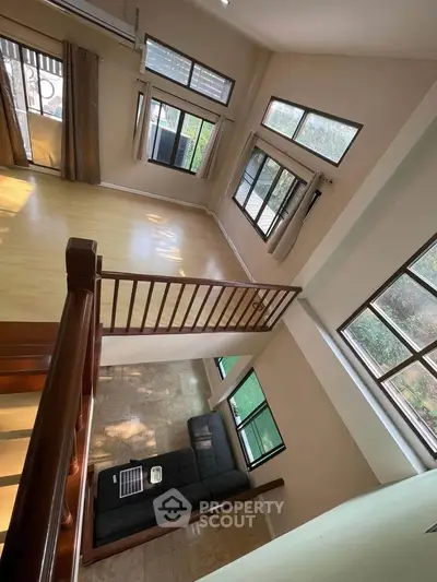 Spacious two-story living room with large windows and wooden flooring, offering abundant natural light and modern design.