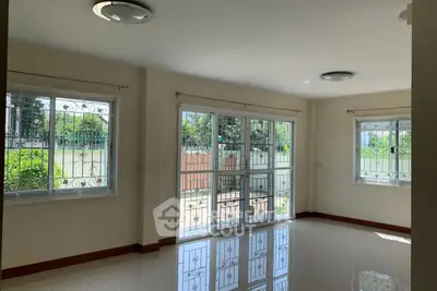 Spacious living room with large windows and garden view, perfect for natural light lovers.