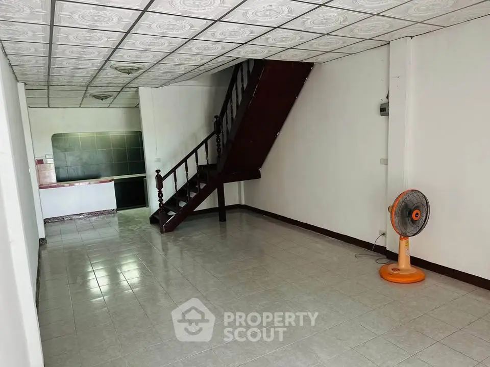 Spacious open-plan living area with staircase and tiled flooring, ideal for customization.