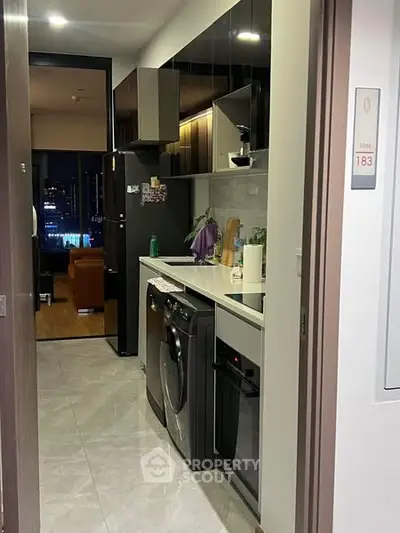 Modern kitchen with sleek appliances and open layout leading to living area.