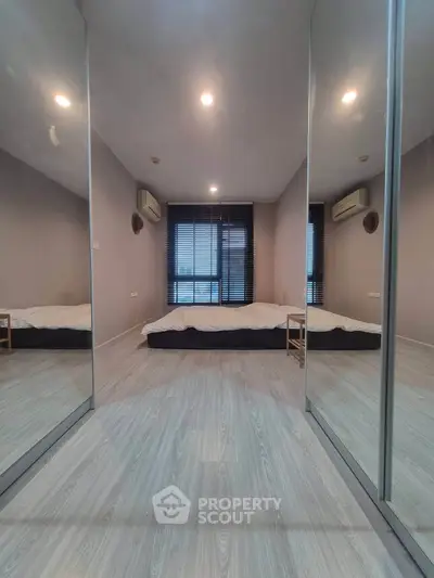 Modern minimalist bedroom with mirrored closet doors and sleek flooring.