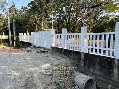 Charming white fence surrounding a serene property with lush greenery, perfect for privacy and tranquility.