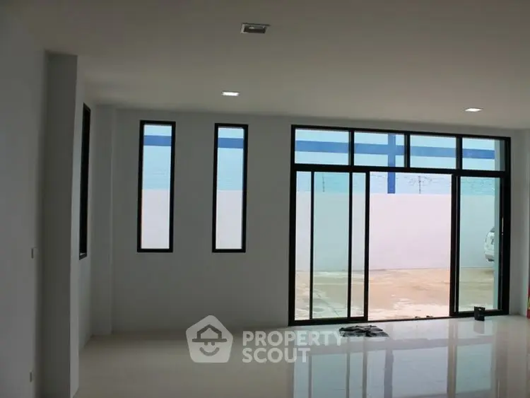 Spacious modern living room with large windows and sleek tile flooring