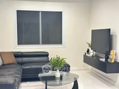 Modern living room with sleek black leather sofa and wall-mounted TV