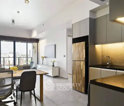 Modern open-plan living room and kitchen with city view, sleek furniture, and natural light.