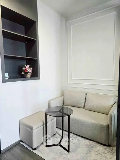 Cozy small living room with modern sofa, glass table, and decorative shelves.
