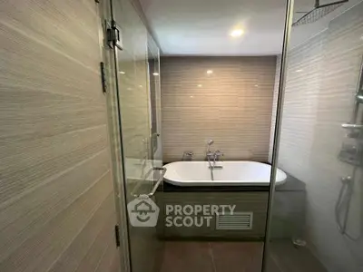 Modern bathroom with glass shower and built-in bathtub in stylish apartment.