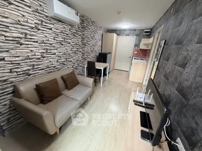 Modern living room with stylish stone accent wall and compact kitchen area.