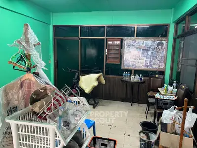 Cozy room with vibrant green walls and eclectic decor, featuring a small seating area and exercise bike.