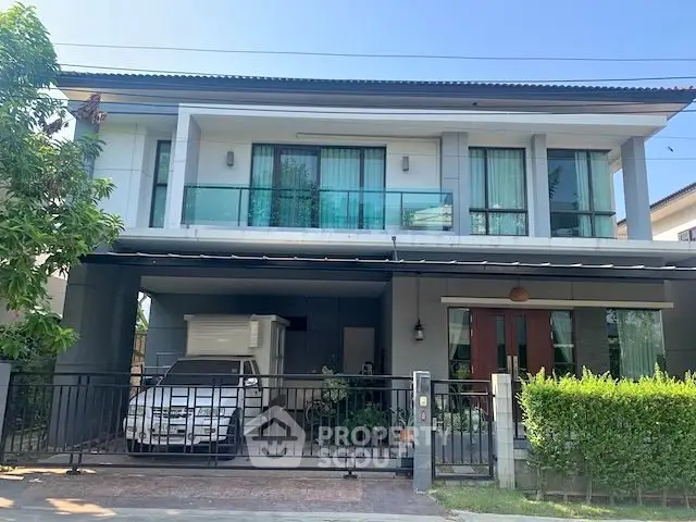 Modern two-story house with balcony and garage in a suburban neighborhood.