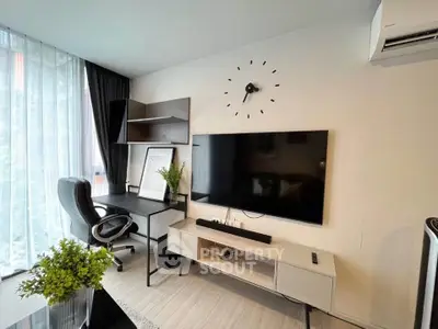 Modern living room with sleek TV setup and stylish workspace, featuring large windows and contemporary decor.