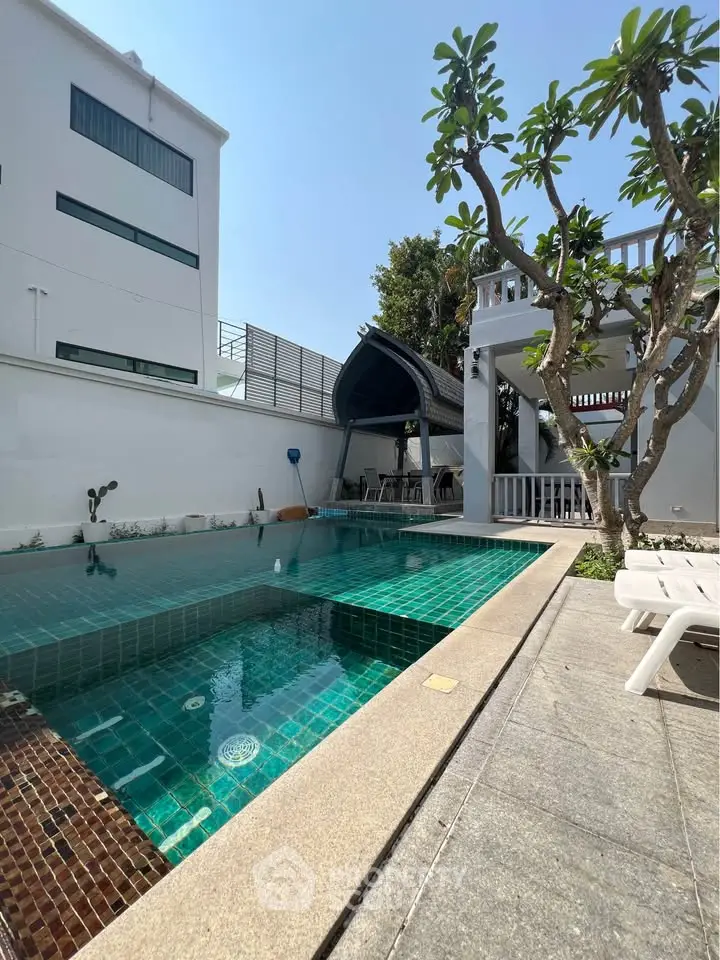Luxurious outdoor pool area with modern design and lush greenery, perfect for relaxation and entertainment.