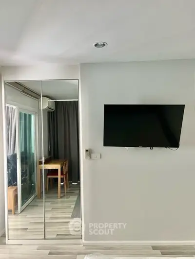 Modern living room with wall-mounted TV and mirrored closet doors