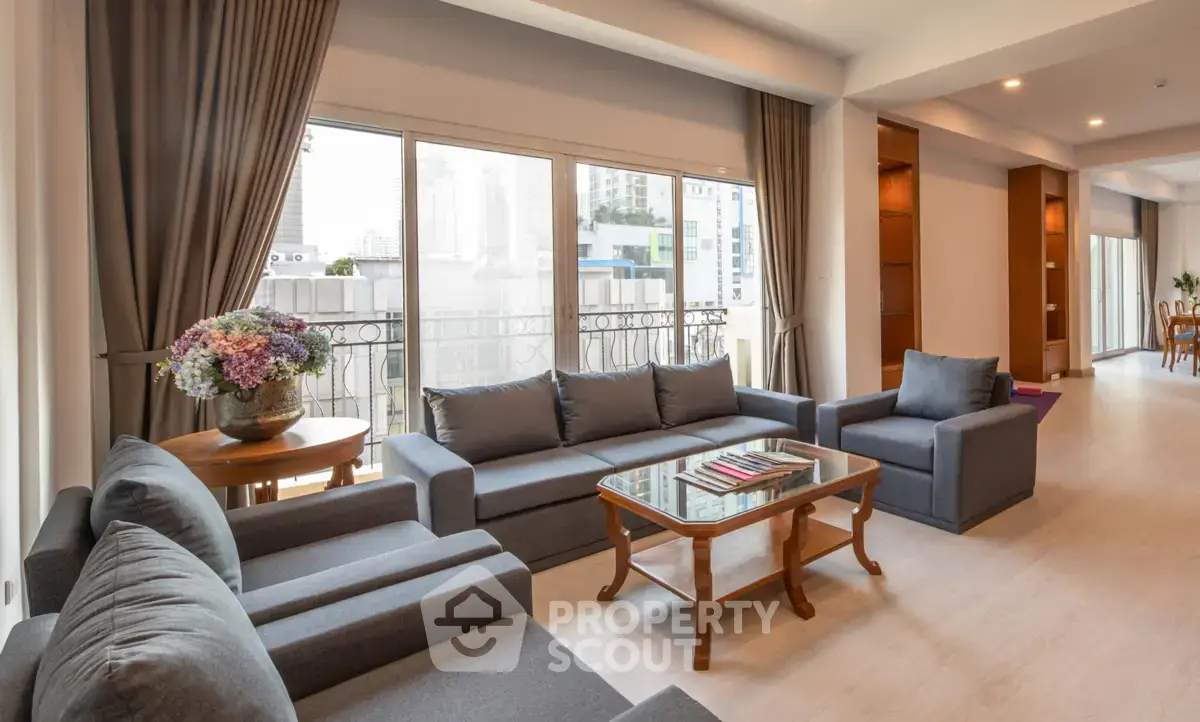 Spacious living room with elegant furniture and large windows offering city views.