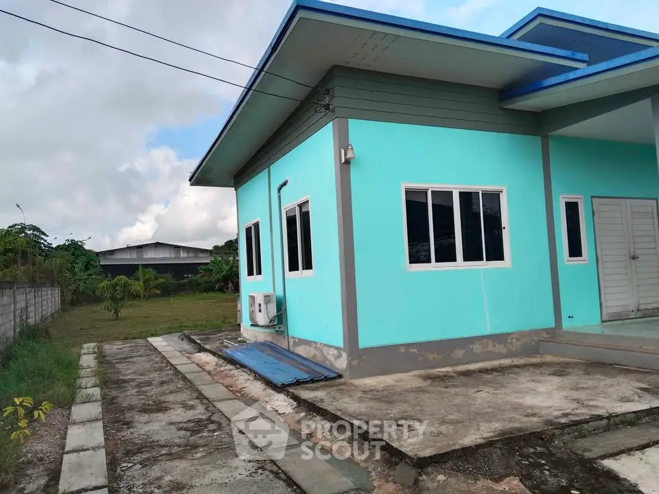 Charming turquoise house with modern design and spacious outdoor area, perfect for family living.