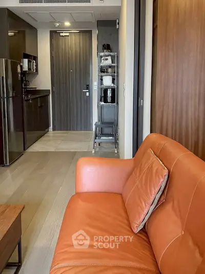Modern apartment interior with sleek kitchen and stylish orange sofa, showcasing contemporary urban living.