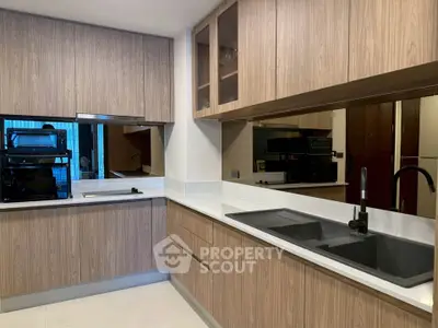 Modern kitchen with sleek wooden cabinetry and dual sinks, featuring a contemporary design and ample storage space.