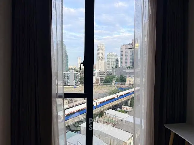 Stunning cityscape view from a high-rise apartment window, showcasing urban skyline and train tracks.