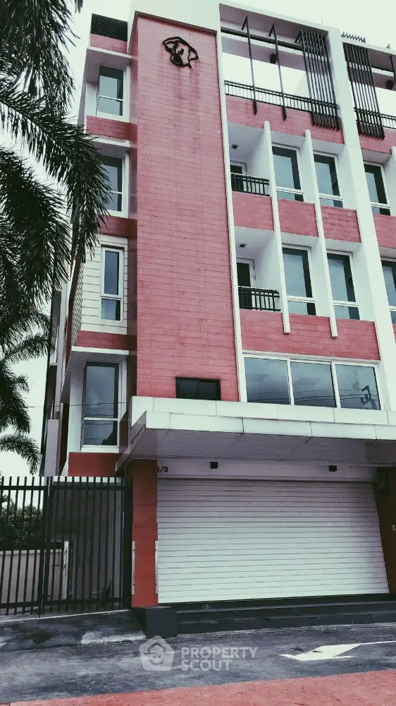 Modern red brick building exterior with gated entrance and large windows