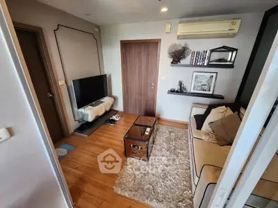 Cozy living room with modern decor and wooden flooring, featuring a TV and air conditioning.