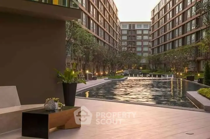 Luxurious apartment complex with serene pool and modern architecture.