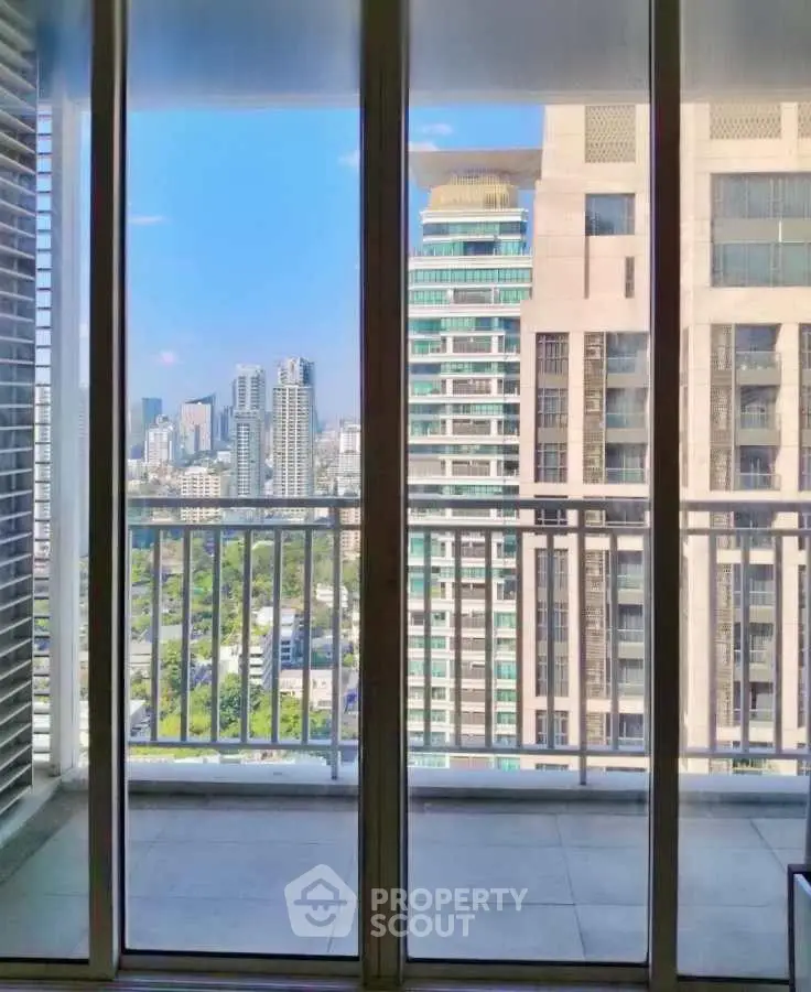 Stunning cityscape view from a high-rise balcony with glass doors and modern architecture.
