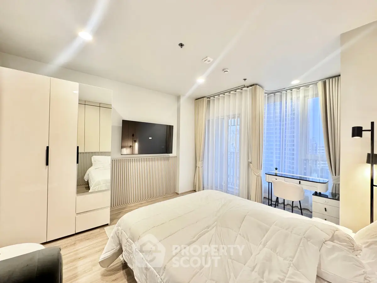 Luxurious bedroom with modern decor and city view, featuring a sleek desk and large wardrobe.