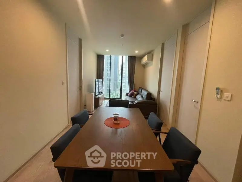 Modern living room with dining area and large window view in a stylish apartment.