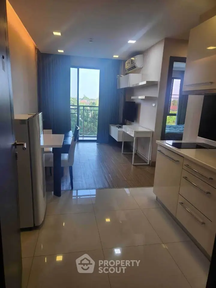 Modern open-layout apartment with sleek kitchen and cozy living area, featuring a balcony with a scenic view.