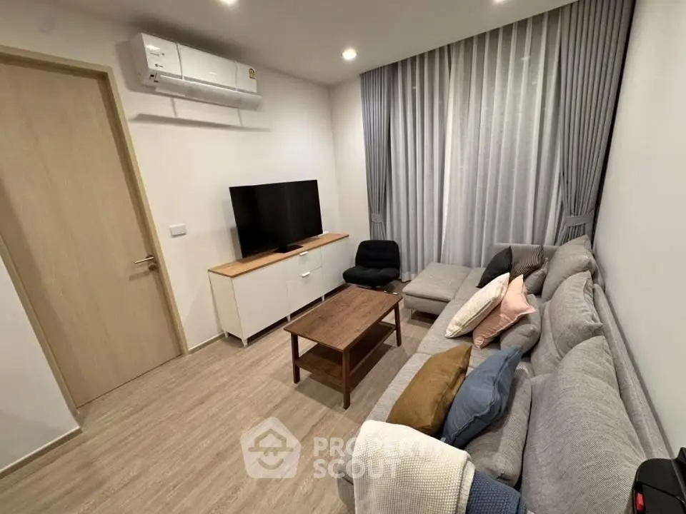Modern living room with cozy gray sofa, flat-screen TV, and stylish decor