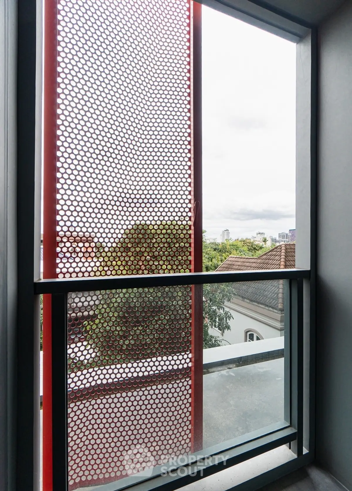 Modern architectural window with unique mesh design and city view.
