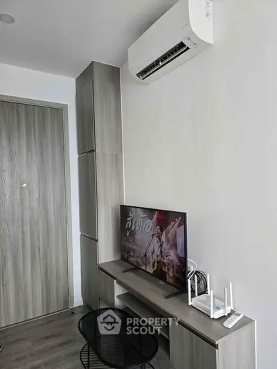 Modern living room with sleek furniture and air conditioning, featuring a flat-screen TV and stylish decor.