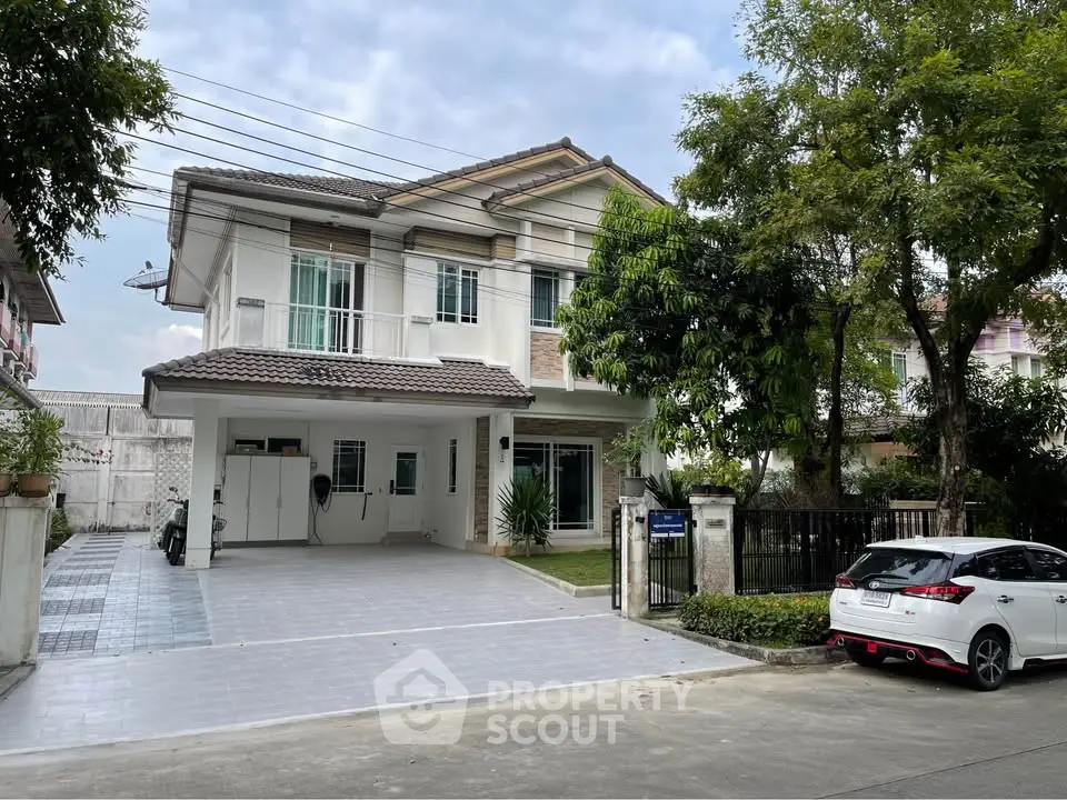 Charming two-story house with spacious driveway and lush greenery in a serene neighborhood.