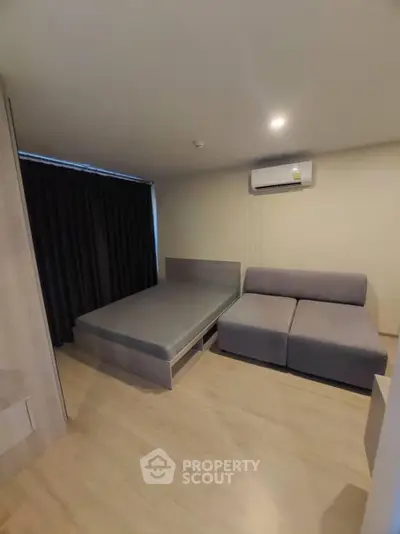 Modern bedroom with minimalist design featuring a bed and sofa under soft lighting.