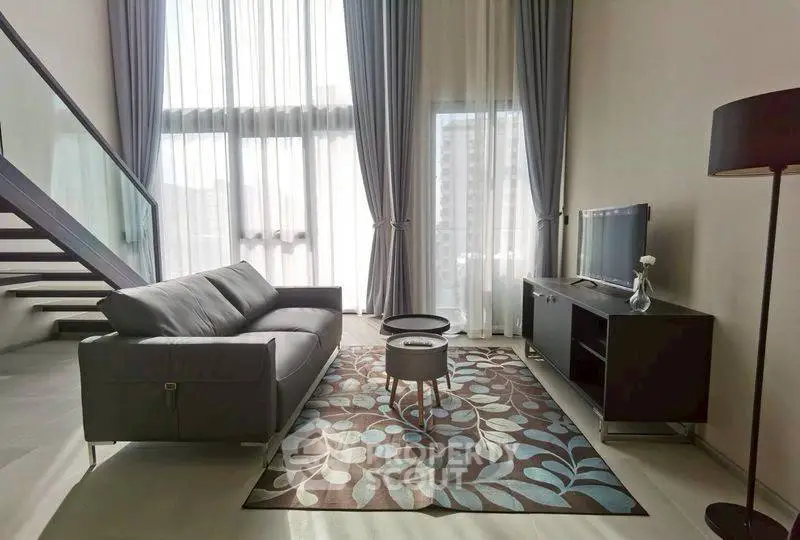 Modern living room with high ceilings, stylish sofa, and large windows offering natural light.