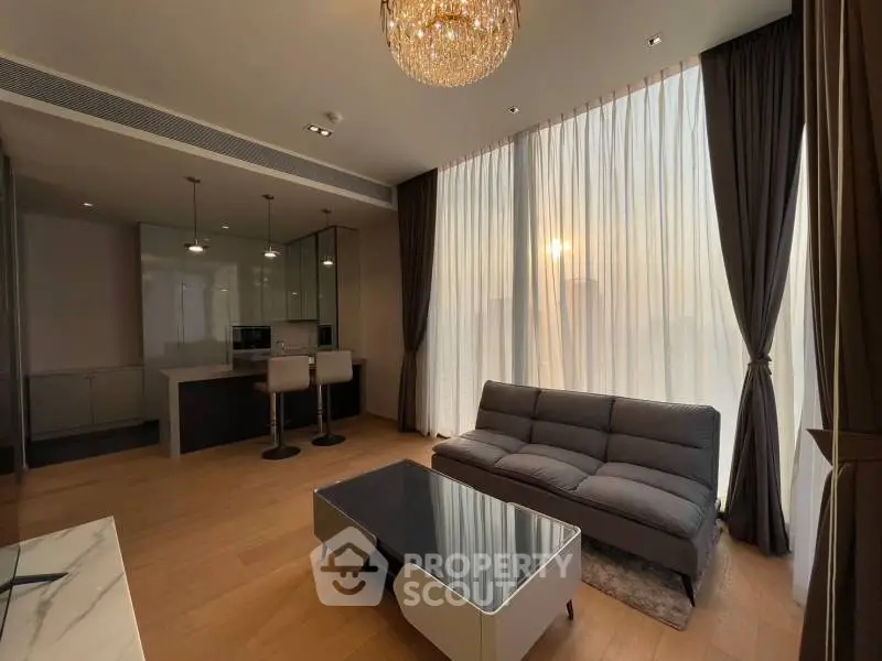 Luxurious modern living room with elegant chandelier and floor-to-ceiling windows.