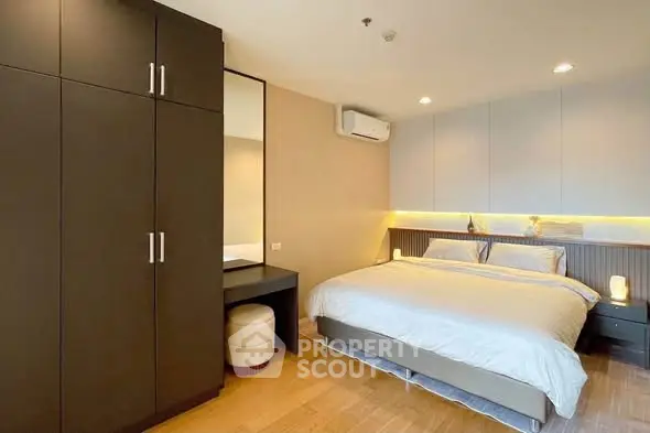 Modern bedroom with sleek design, featuring a large bed, built-in wardrobe, and ambient lighting.
