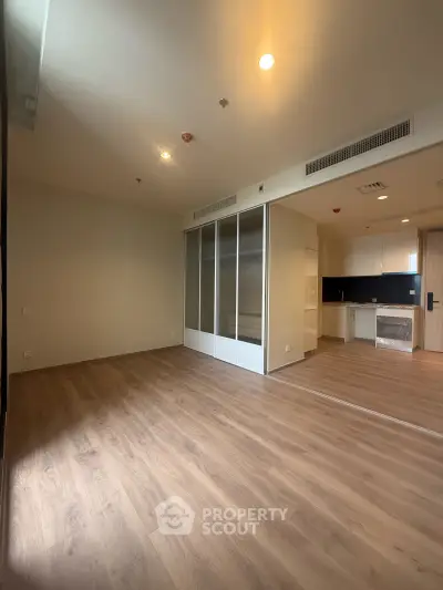 Spacious modern living room with wooden flooring and open kitchen layout in a stylish apartment.