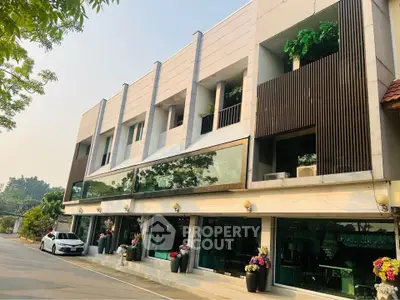 Modern multi-story building with large windows and greenery, ideal for commercial or residential use.