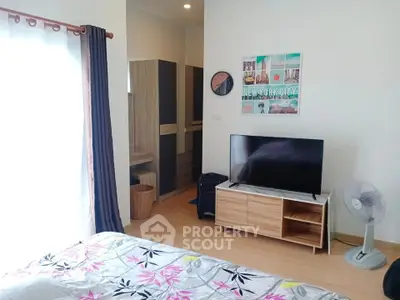 Cozy bedroom with modern decor, featuring a TV, fan, and stylish furniture, perfect for relaxation.